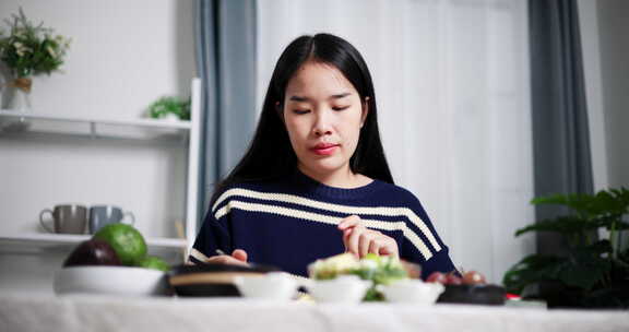 一个年轻的女人在家里的桌子上准备沙拉吃，