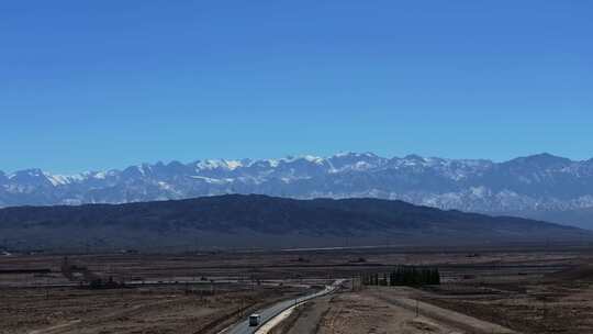 大气航拍西北戈壁滩上的公路及远方的雪山