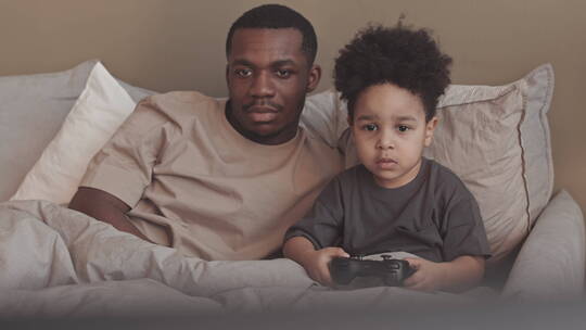 男孩和爸爸在床上玩电子游戏