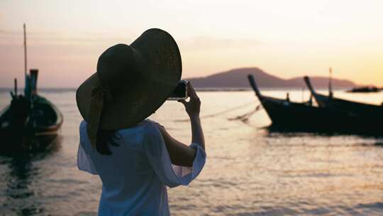 女人海边用手机拍摄夕阳