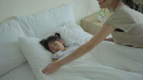 亚洲美丽的母亲轻轻地把毯子放在熟睡的女孩身上视频素材模板下载