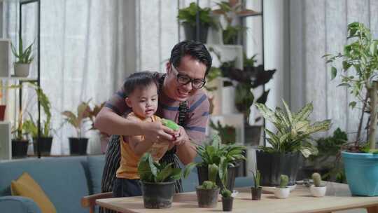 快乐的亚洲男人带着儿子在家给植物浇水