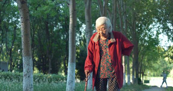 老年女性拄着拐杖在公园散步