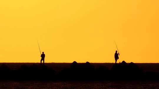日落时钓鱼的人影