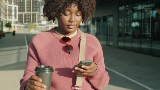 女人端着咖啡玩手机
