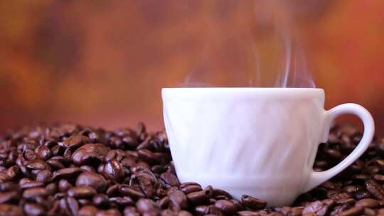 摇摄咖啡豆堆里冒着热气的咖啡杯