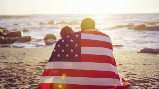 裹着美国国旗的夫妇坐在海滩上4k