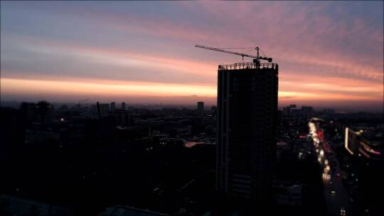 日落时城市建筑起重机的鸟瞰