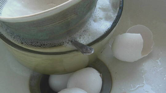 水流入装有脏盘子和蛋壳的水槽