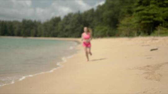 穿着粉色运动服在海滩上跑步的女人