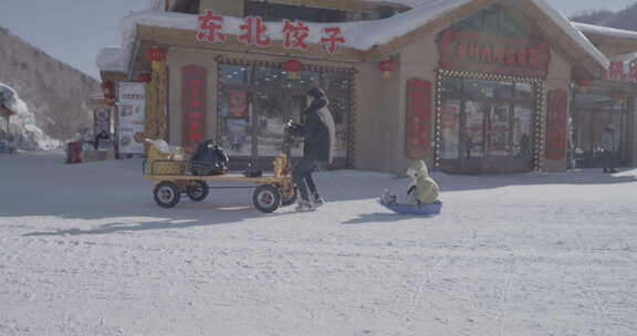 东北饺子馆前男子拉车孩童坐雪橇的场景