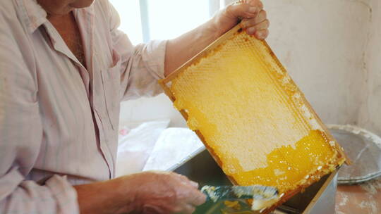 老年人刮掉新鲜蜂蜜的表层