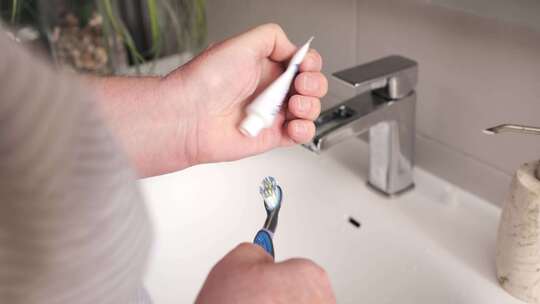 男子在家将牙膏涂在牙刷上清洁牙齿视频素材模板下载