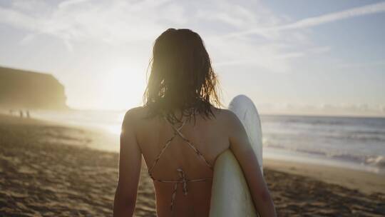 女人拿着冲浪板在海滩