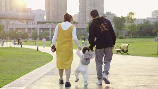 幸福的一家三口  父母牵着孩子学习走路