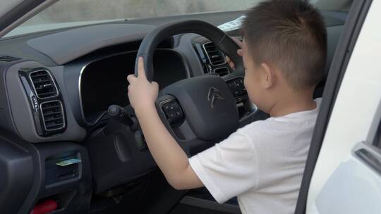 孩子坐在汽车驾驶座上假装开车游戏
