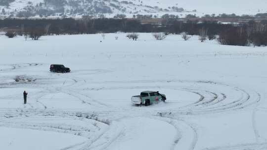 雪地中两辆汽车行驶及一人拍摄