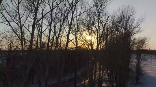 雪地公路迎着夕阳孤独行驶航拍