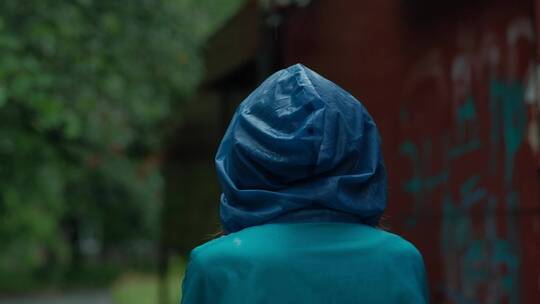 雨天女人穿着雨衣走在街道上视频素材模板下载