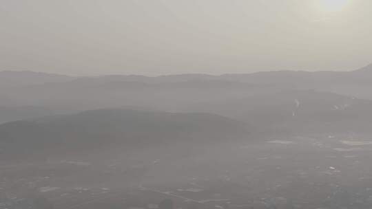 云南阳光下雾气笼罩的杨梅林山坡村庄航拍
