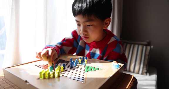 中国小孩在窗边下棋跳跳棋