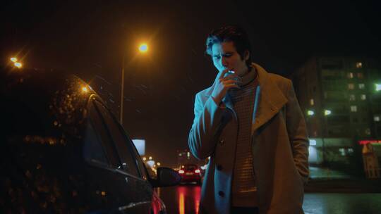 夜晚男人站在车旁抽烟