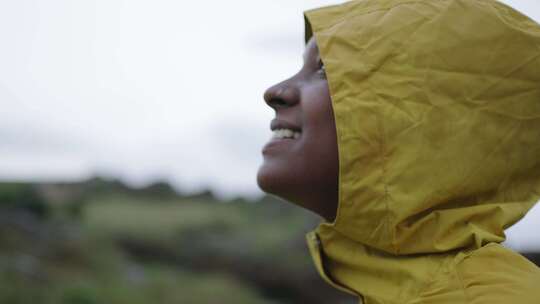 自然景观中穿着黄色雨衣的年轻微笑的非裔美