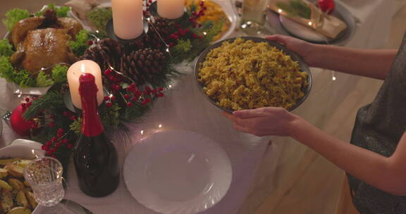 圣诞节女人把米饭放在餐桌上