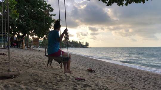 海滩树下荡秋千的女人