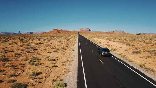 银色汽车沿着令人惊叹的美国沙漠公路驶向山脉的美丽航拍视频素材模板下载