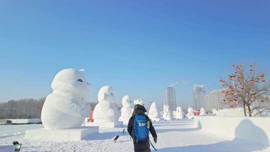 背着背包的人走在雪雕展览场地中生肖大雪人