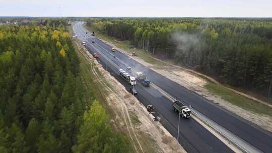 沥青摊铺机、道路工人和高速公路上滚筒的俯视图