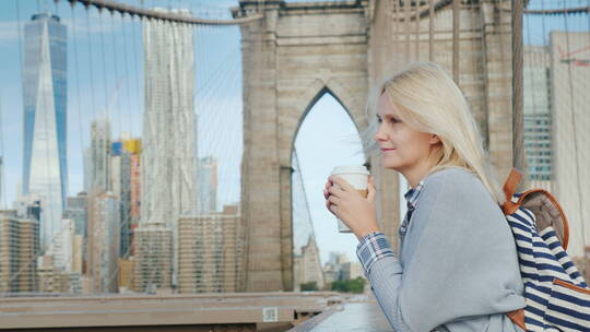 手拿咖啡站在大桥上的女人