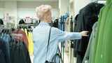 一个女人走过商店，看着架子上的外套高清在线视频素材下载