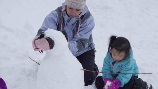 小女孩和一个女人在堆雪人