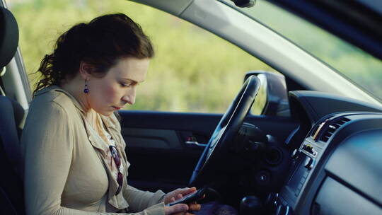女人坐在车里悲伤的看手机