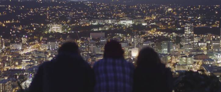 趴在山顶看城市夜景的三人