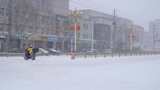 4k北方城市下大雪的马路推着电动车的行人高清在线视频素材下载