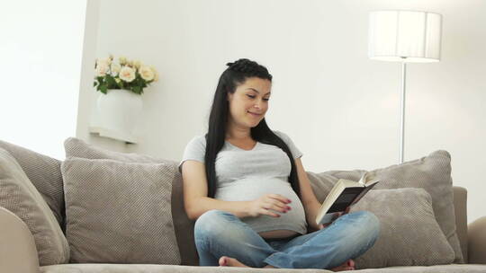 孕妇坐在沙发上看书视频素材模板下载