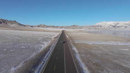 航拍冬季新疆赛里木湖环湖车辆行驶雪山公路