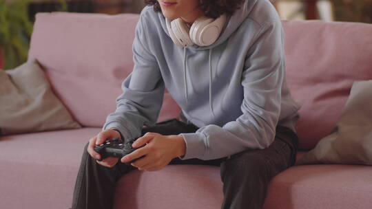 男孩坐在沙发上玩电子游戏