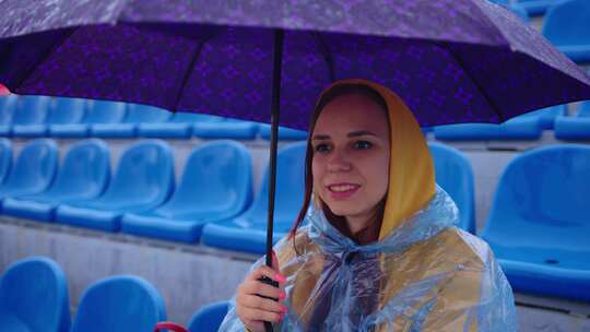 雨中穿着雨衣打着雨伞的年轻女子独自坐在体