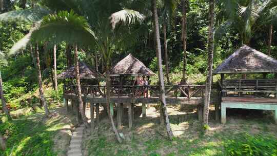 4K无人机镜头从一对站在竹屋旁边俯瞰蓝色