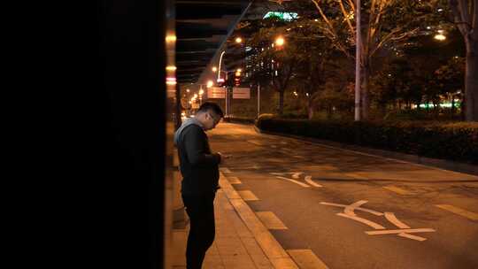 夜晚男子在公交牌等车