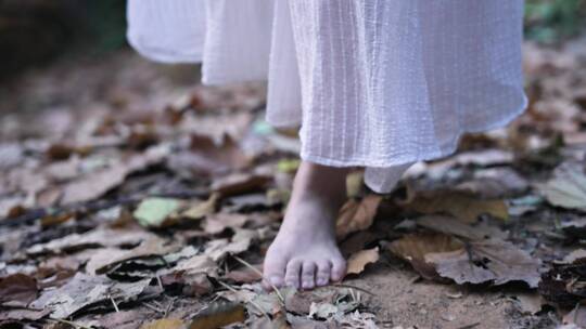穿着长裙的女孩赤脚在落叶上行走4k视频素材