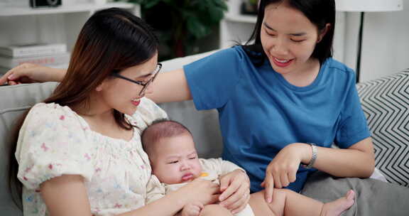 两个年轻的亚洲女人在家里开心地和一个婴儿