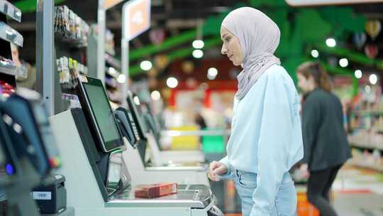 女买家在超市使用自助收银员结账。客户扫描