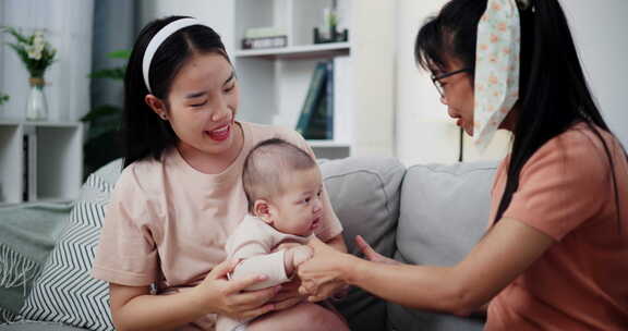 两个女人在家里客厅的沙发上开心地和一个小