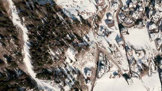 自上而下的无人机在蜿蜒的道路上向被雪覆盖的滑雪小屋射击