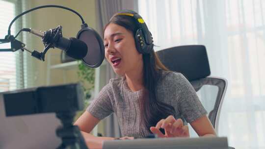 亚洲有吸引力的音频DJ女人对着麦克风说话广播。